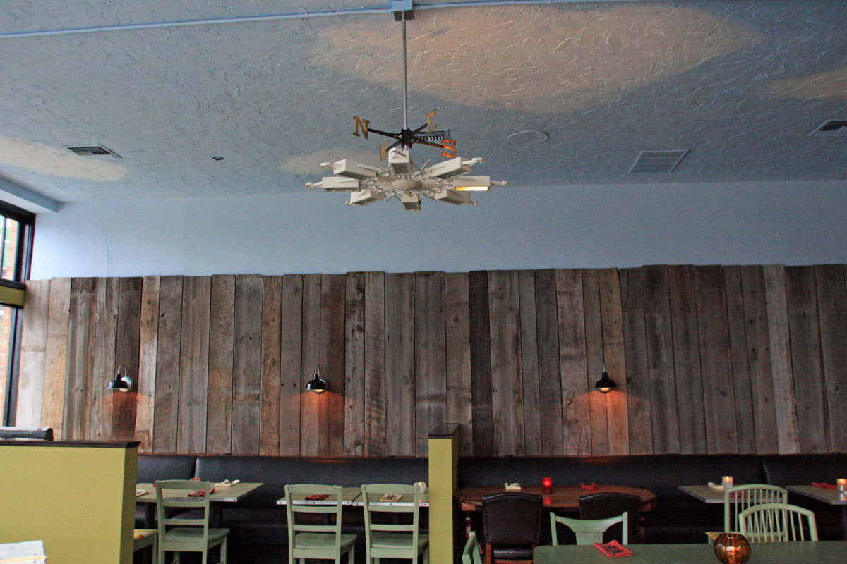 Salvaged barn wood lines the wall, while an equally salvaged chandelier serves as a weathervane.