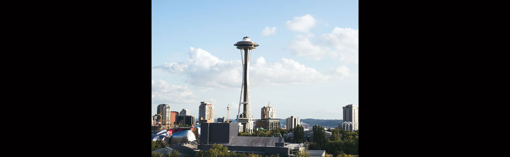 The Seattle World’s Fair was originally intended to be a “festival of the West” marking the 50th anniversary of the Alaska–Yukon–Pacific Exposition. Boosters hoped it would bring new energy downtown, then being drained by the postwar flight of inhabitants to the suburbs. But in October 1957, the Soviets launched Sputnik, catapulting America into the Space Race, and fair organizers realized they could harness federal funds if they focused the event on science and technology. Thus Century 21 was born. Supposedly first sketched by hotel executive Eddie Carlson on a cocktail napkin after dining atop Germany’s Stuttgart TV Tower, the Space Needle was constructed with $4.5 million of private investment in just over a year. The 605–foot–high steel tripod, topped with saucer–shaped revolving restaurant and observation deck, originally sported a space–age color scheme of astronaut white, reentry red, orbital olive, and galaxy gold (the last briefly restored for the fair’s 50th anniversary last summer). Nearly 20,000 people rode the high–speed elevators to the top of the Needle each day during the fair, while the building now hosts over a million visitors each year. The Needle continues to fulfill the goals of its creators, who wanted to build both a permanent landmark and iconic symbol of Seattle.
